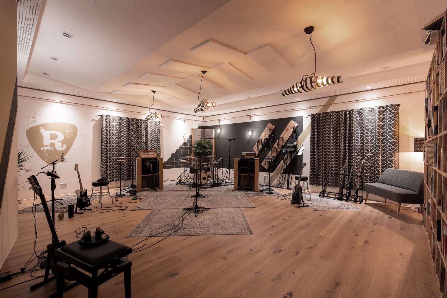Modern eingerichteter großer Aufnahmeraum in einem Tonstudio mit verschiedenen Musikinstrumenten und Audioausrüstung.