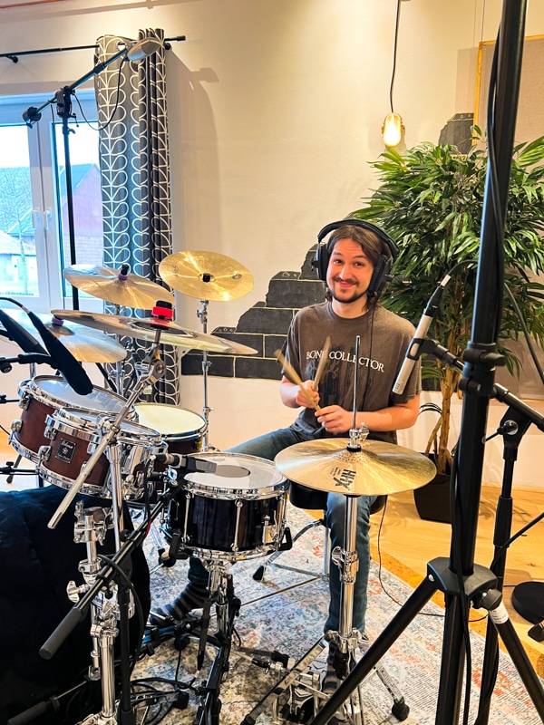 Schlagzeuger spielt lächelnd während der Recording Session